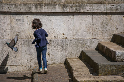 Rear view of woman standing against wall