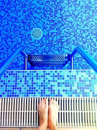 Low section of man standing by swimming pool