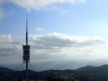 Communications tower against cloudy sky