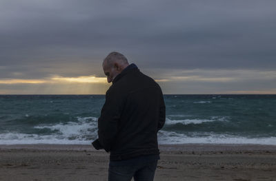 Adult man in winter clothes on beach during sunset. almeria, spain