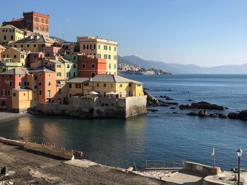 Buildings by sea against clear sky