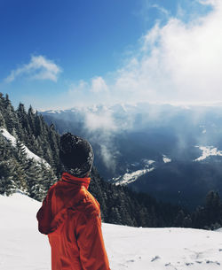 Rear view of person standing on snowcapped mountain against sky