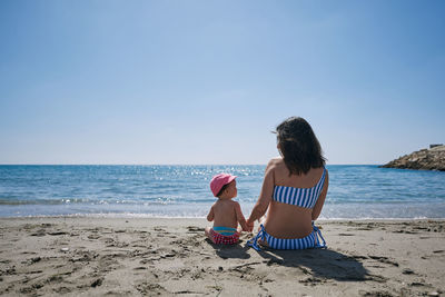 A young mother playing with her baby on the seashore. concept of reconciliation, play, love, holiday