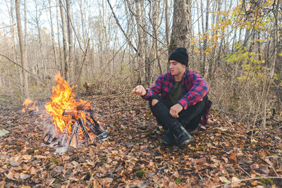 Man roasting food in campfire at forest