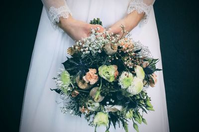 Midsection of bride holding flower bouquet
