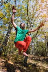 Mature male athlete doing a sitting trick while standing on the slackline