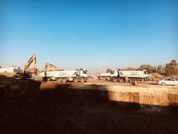 Cranes at construction site against clear blue sky