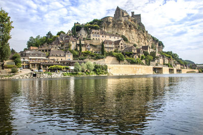 Old building by river against sky