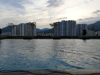 View of buildings by swimming pool against cloudy sky
