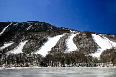 Scenic view of snowcapped mountains against clear blue sky