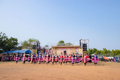 Group of people playing soccer on sand against clear sky