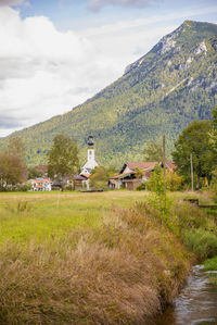 Scenic view of field by houses against sky