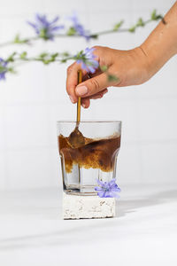 A woman's hand will pour granulated chicory powder into a white mug. drink chicory.