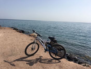 Bicycle by sea against clear sky