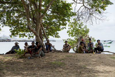 Group of people sitting on land against trees