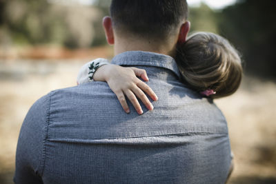 Rear view of father carrying daughter on field