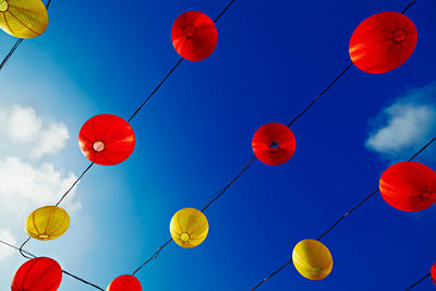 Low angle view of lanterns hanging against blue sky