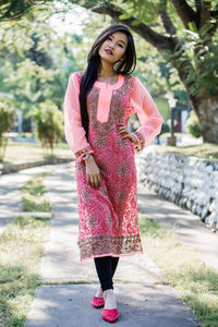 Portrait of young woman standing against pink umbrella