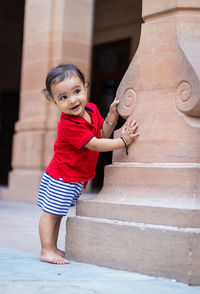 Toddler baby boy cute facial expression standing with wall support in casual appearance at outdoor