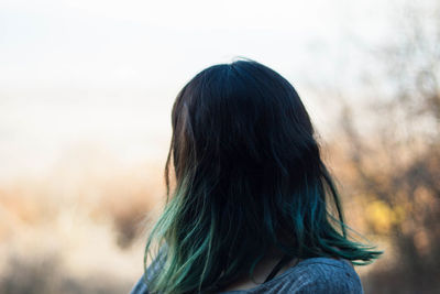 Woman with dyed hair against sky during sunset