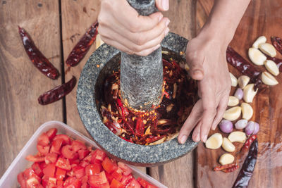 Cropped hands of woman crushing red chili pepper in mortar and pestle