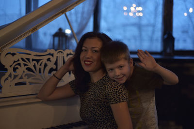 Portrait of smiling woman with son by grand piano