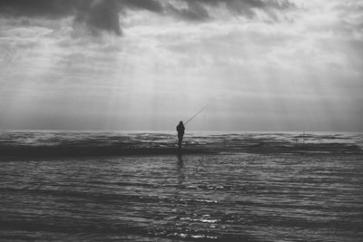 Silhouette of man fishing at seaside