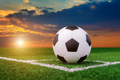 Digital composite of soccer ball on playing field against sky 