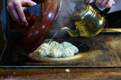 Midsection of man pouring drink on dumplings