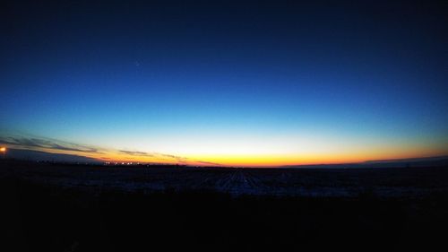 Scenic view of silhouette field against sky at sunset