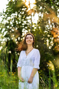 Portrait of smiling young woman standing against plants