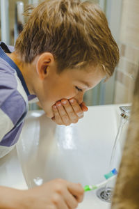 Close-up of boy brushing teeth at bathroom