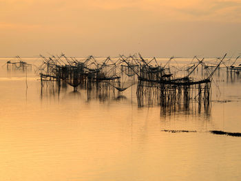 Fishing net in sea against sky during sunset