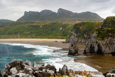 Scenic view of rocks by sea against sky