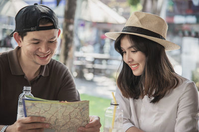 Smiling couple holding map sitting at restaurant