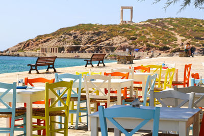 Chairs and tables at beach against clear sky