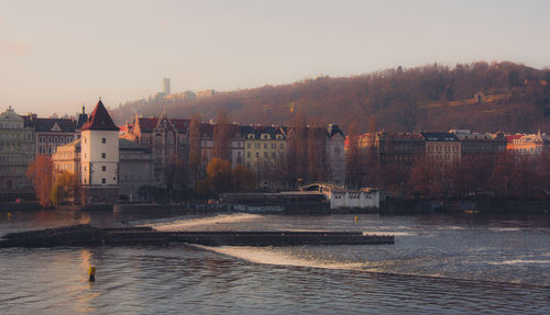 River by buildings against sky during sunset