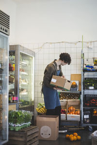 Male owner with fruit box standing in store