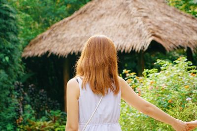 Rear view of woman with blond hair standing against tree