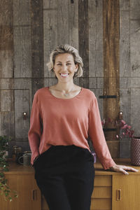 Portrait of smiling businesswoman leaning on sideboard against wood paneling in portable office truck