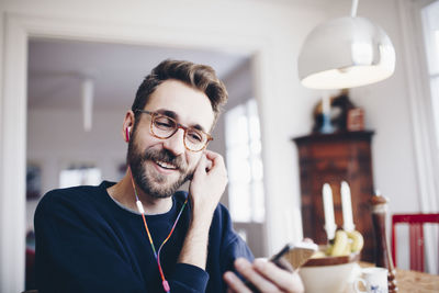 Happy man listening to music in mobile phone at home