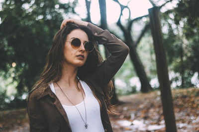 Portrait of beautiful woman wearing sunglasses against trees