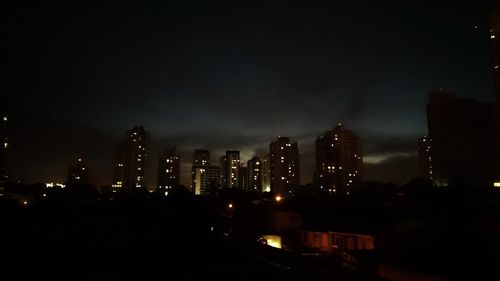 Illuminated buildings in city against sky at night