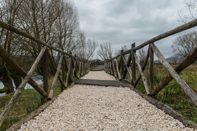 Footbridge amidst trees against sky