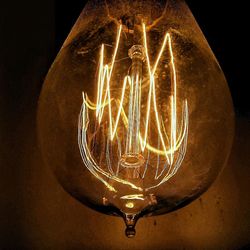 Close-up of illuminated light bulb over black background