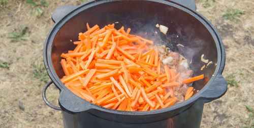 Cooking pilaf in a cast-iron wok in the open air. lots of sliced carrots and meat fried in a wok 