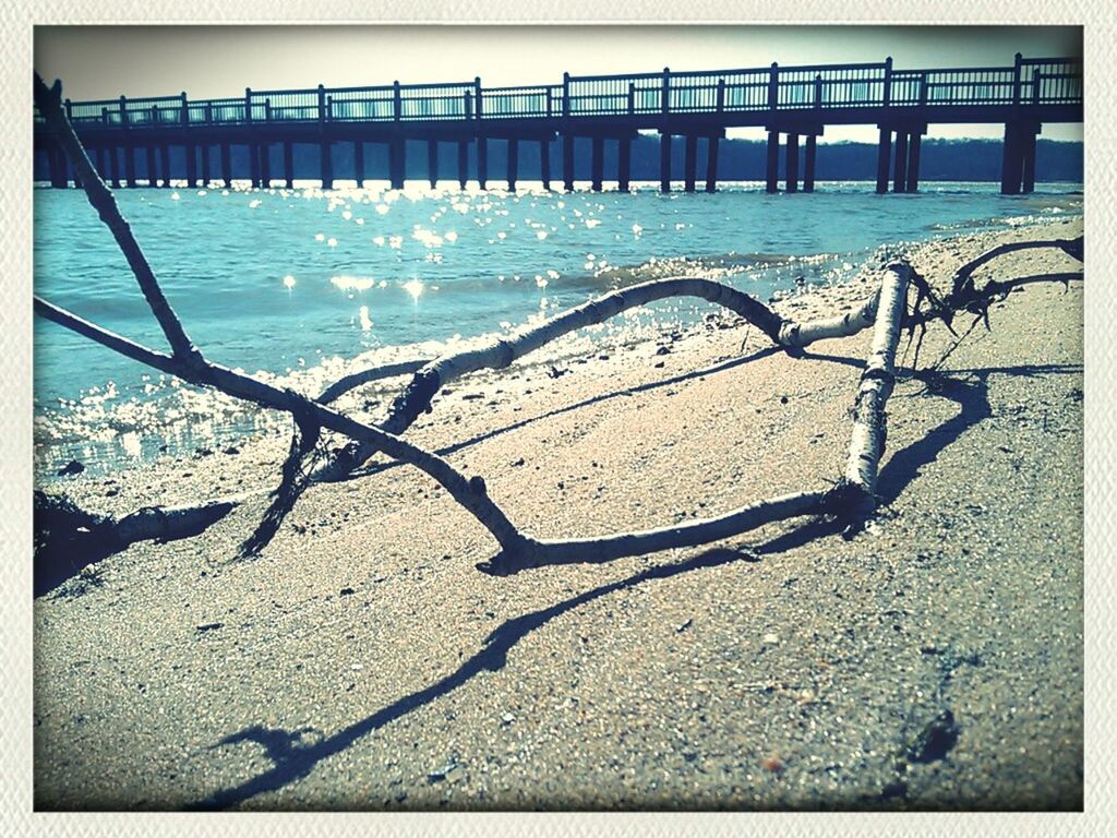 transfer print, water, beach, sand, sea, auto post production filter, shore, built structure, shadow, sunlight, nature, architecture, day, outdoors, no people, tranquility, sky, railing, river, high angle view