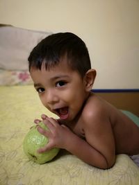 Portrait of smiling girl eating fruit on bed at home