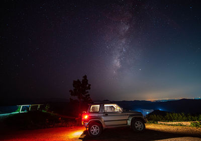 Car against illuminated road against sky at night