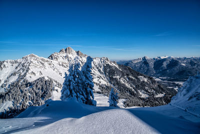 Scenic view of snow covered mountains against blue sky